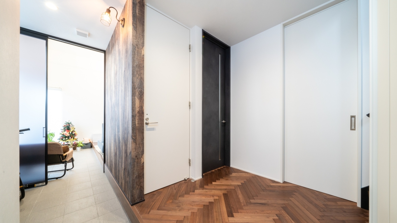 ヘリンボーンの床と、木目のアクセントが印象的な玄関