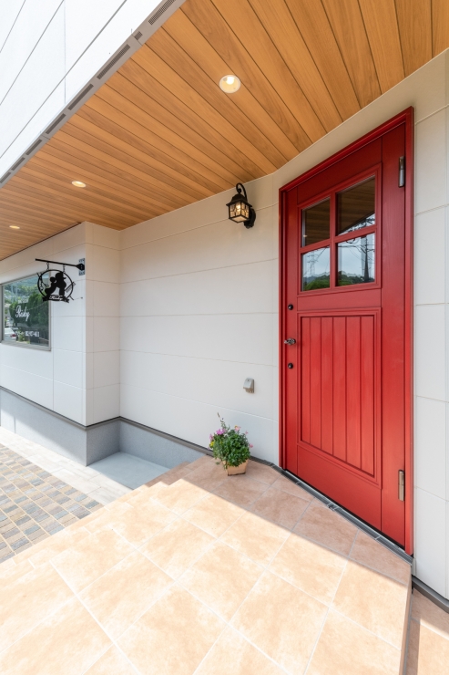 赤いドアと木の軒天が印象的なナチュラルなアプローチ